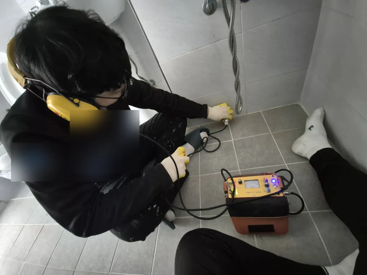 청음식 누수탐지기로 바닥 배관 누수 지점을 찾는 장면